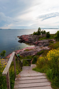 Wooden railing by sea against sky at suomenlinna helsinki