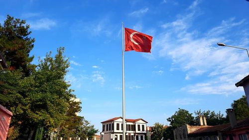 Low angle view of flag by building against sky