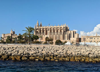 View of building by sea against clear blue sky