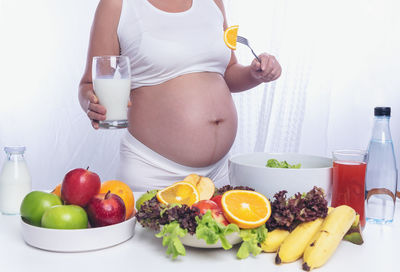 Midsection of pregnant woman having food while standing by table