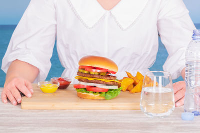 Midsection of woman with drink on table