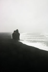 Rock formation on beach against clear sky