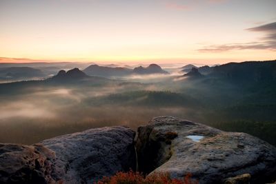 Fantastic dreamy sunrise on the top of the rocky mountain with the view into misty valley