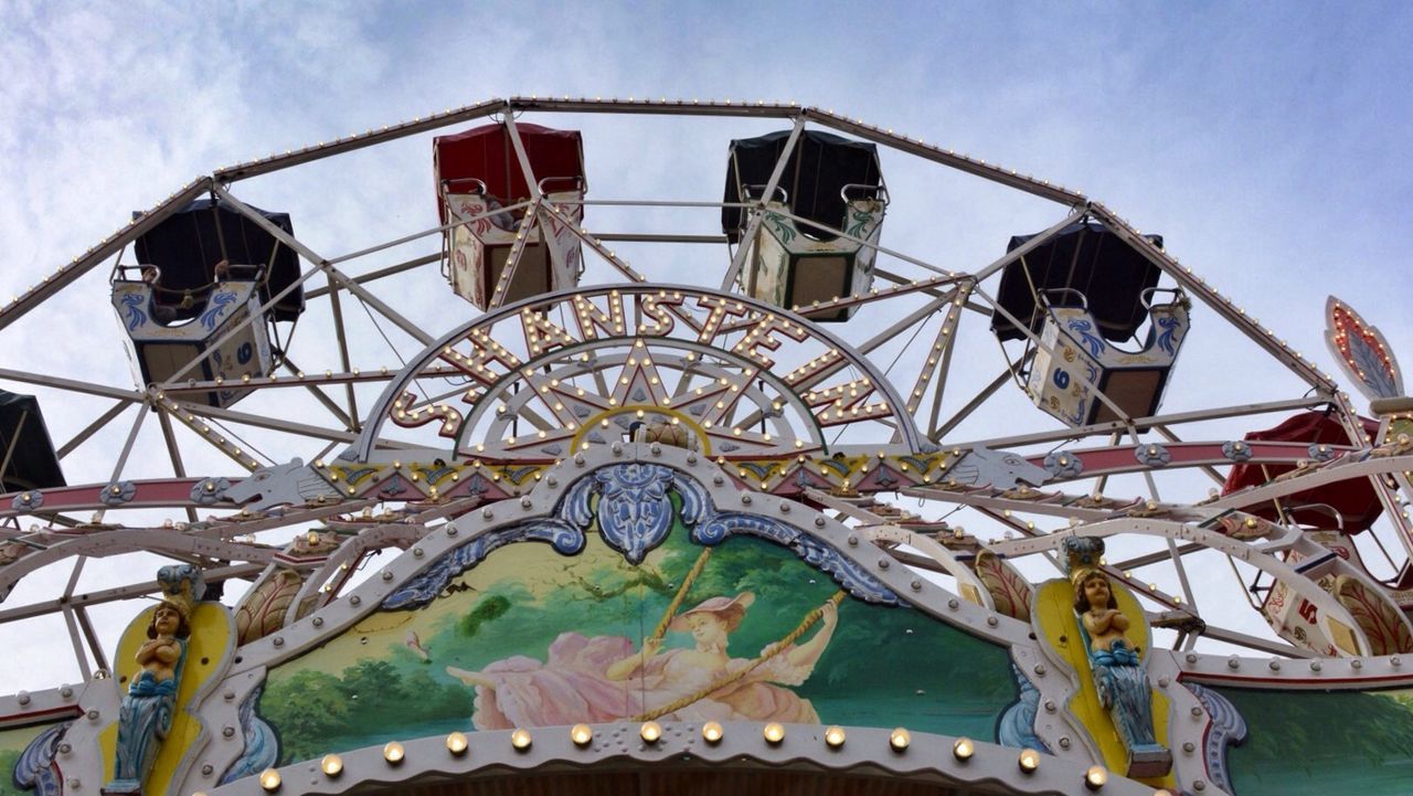 sky, low angle view, nautical vessel, day, flag, hanging, outdoors, amusement park, no people, cloud - sky, boat, sunlight, part of, rope, cloud, blue, mode of transport, transportation, nature, built structure