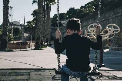 Rear view of boy swinging at playground