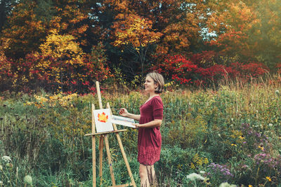 Woman with umbrella standing on field during autumn