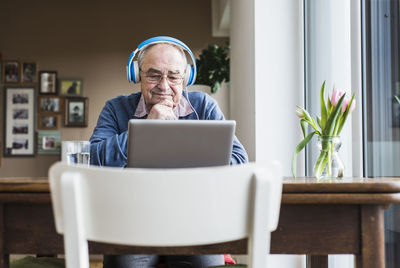 Senior man using laptop and headphones at home