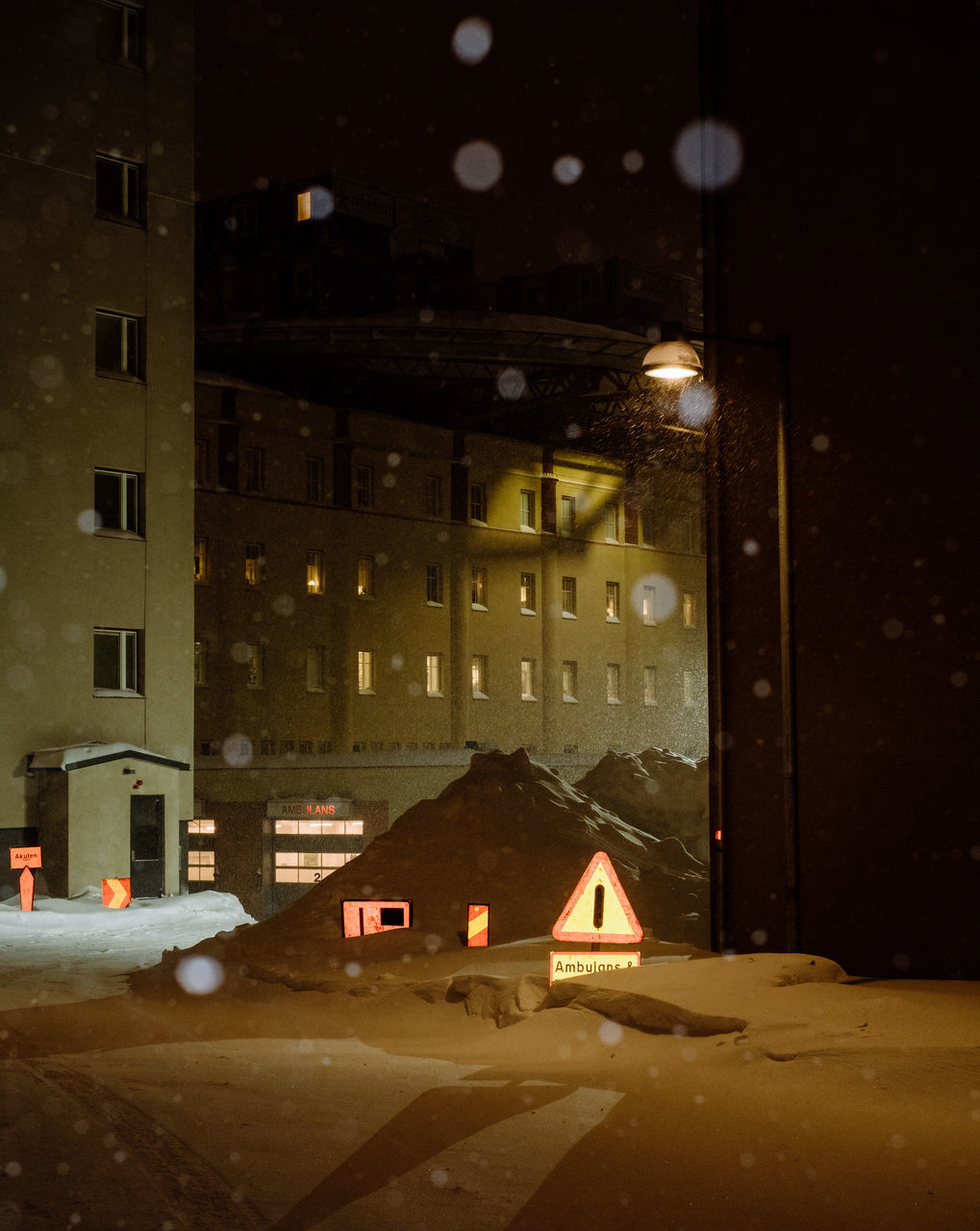 ILLUMINATED BUILDING BY STREET IN CITY DURING WINTER