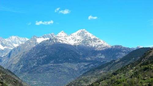 Scenic view of snowcapped mountains against blue sky