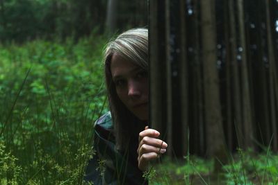 Portrait of young woman by mirror at forest