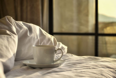 Close-up of coffee cup on bed