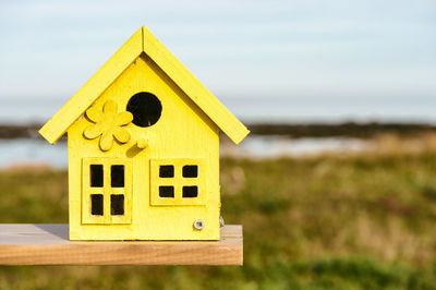 Close-up of yellow wooden birdhouse on field