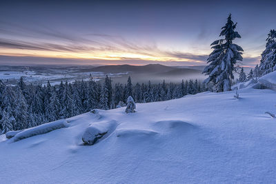 Scenic view of snow covered field against sky at sunset