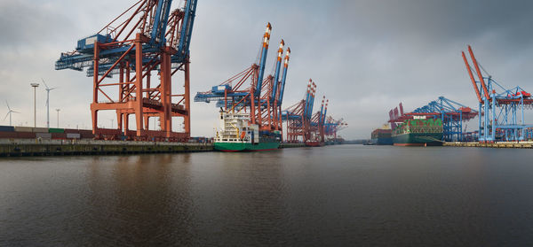 Cranes at commercial dock against sky