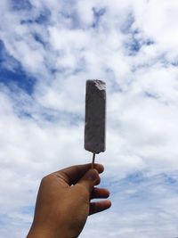 Midsection of person holding ice cream against sky