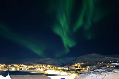 Illuminated snowcapped mountains against sky at night during winter