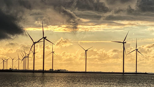 Silhouette of wind turbine against sky during sunset