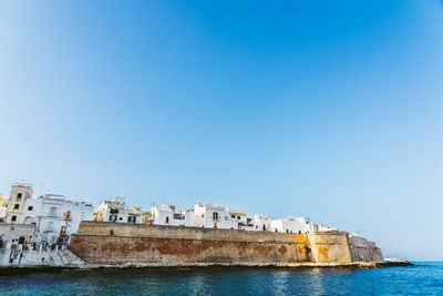 Sea by buildings against clear blue sky