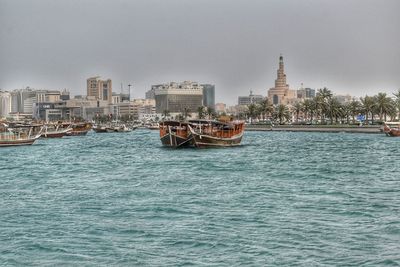 Boats in sea against buildings in city