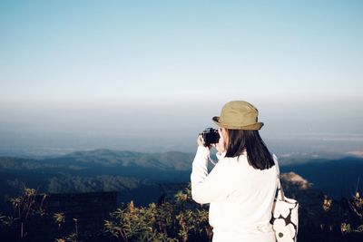 Woman photographing against sky