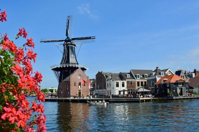 Traditional windmill by building against sky