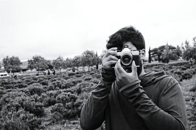 Portrait of man photographing on field