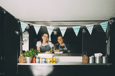 Smiling female owner and assistant standing in food truck