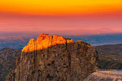 Rock formation by sea against sky during sunset