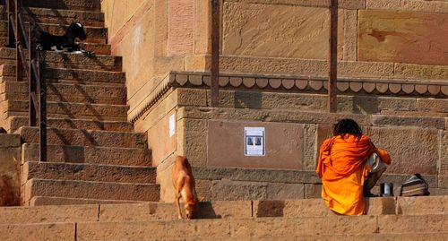 Rear view of man with dog against wall