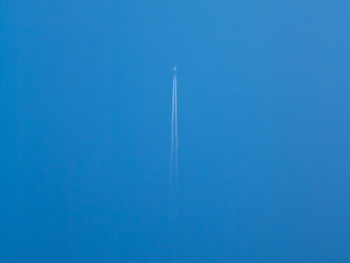 Low angle view of vapor trail against clear blue sky