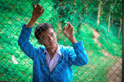 Boy standing by chainlink fence