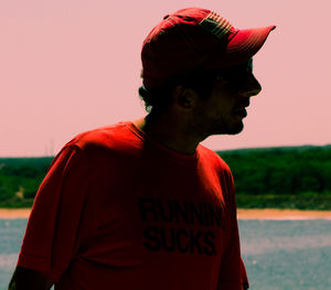 Man looking away while standing against sky