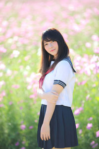 Side view of young woman standing against plants