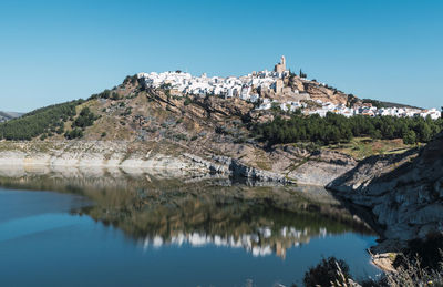 Scenic view of lake and mountains against clear blue sky