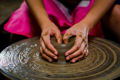 Midsection of woman making pottery in workshop