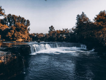 Scenic view of waterfall in forest against sky