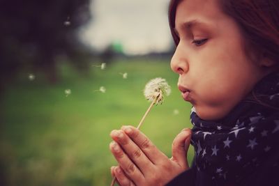 Close-up of girl blowing dandelion seeds