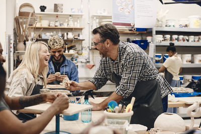 Cheerful mature man laughing with woman while teaching in art class