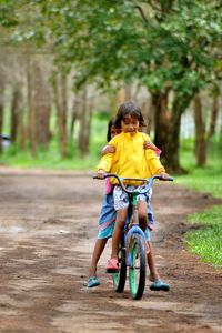 Rear view of boy riding bicycle on road