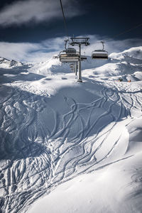 Ski lift on snow covered mountain against sky