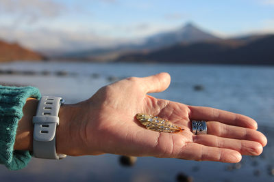 Close-up of hand holding ring over sea