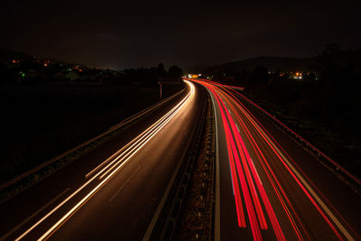 Many red car light trails on a road glowing