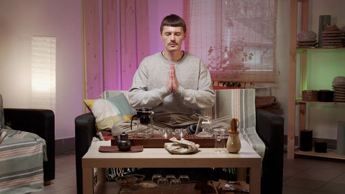 Man with closed eyes meditating at home