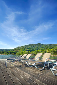 Empty chairs on land against blue sky