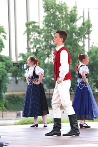 Rear view of friends standing against red umbrella