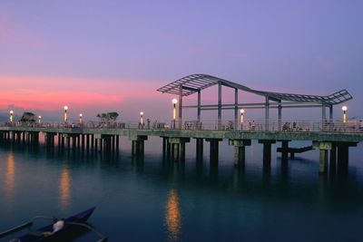 Gazebo by river against sky at sunset