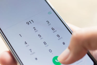 Cropped hand dialing number in mobile phone