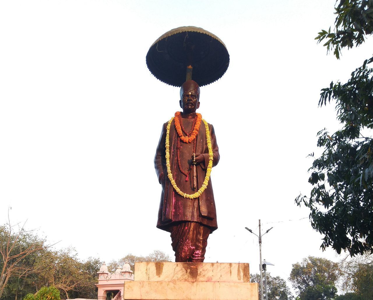 LOW ANGLE VIEW OF STATUE AGAINST TREES AGAINST CLEAR SKY