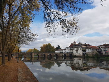 Arch bridge over river by buildings against sky