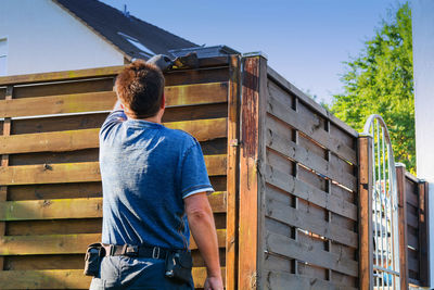 Rear view of man painting wooden fence